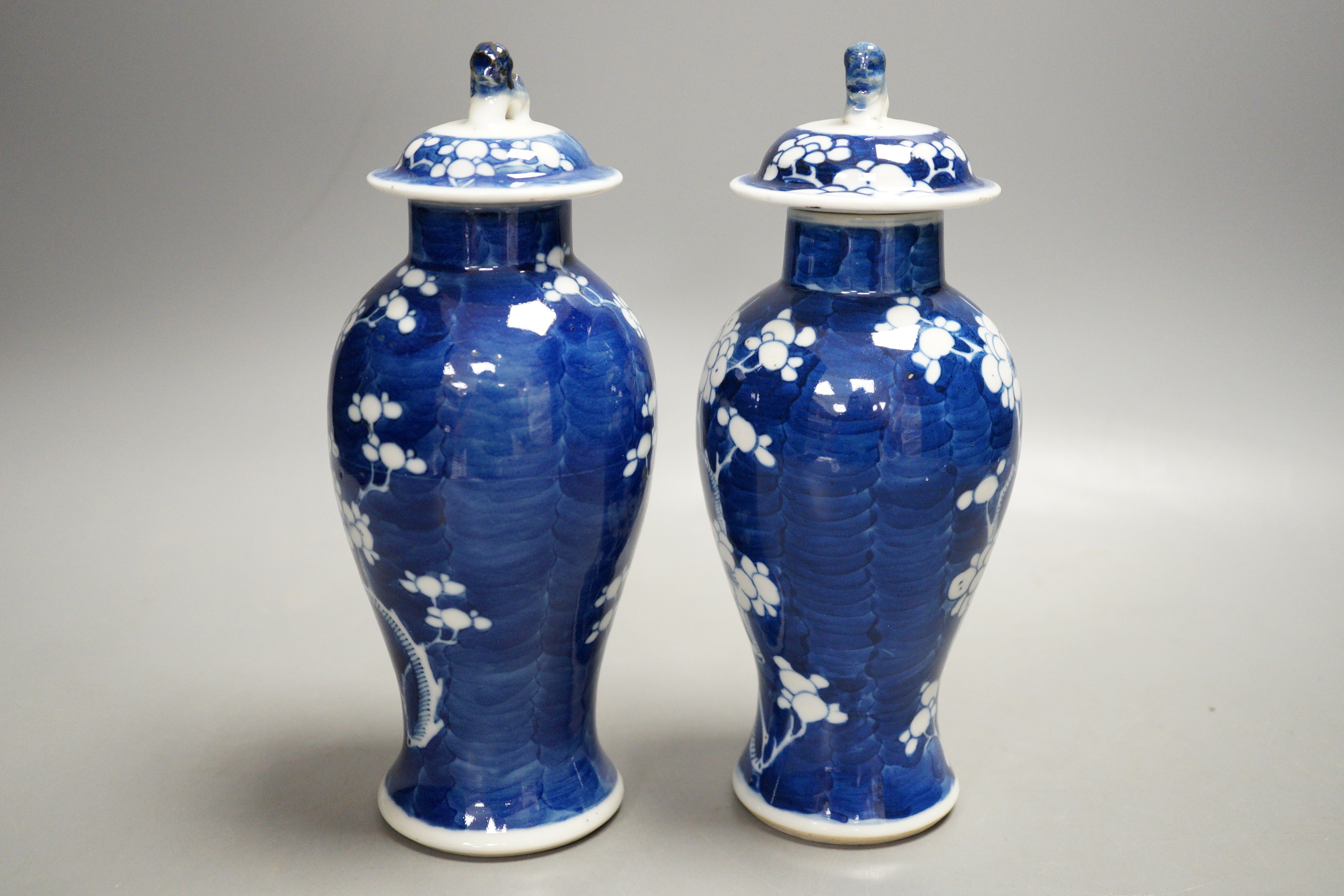 A pair of early 20th century Chinese blue and white ‘prunus’ vases and covers, 21cm